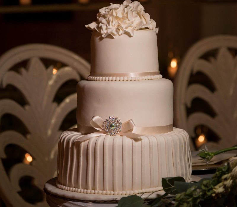 Three tiered white fondant wedding cake topped with buttercream flowers Pasteles de Múltiples Capas | Wink Eventos